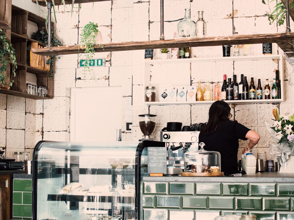 Interior de una cafetería con la barra y el personal al fondo